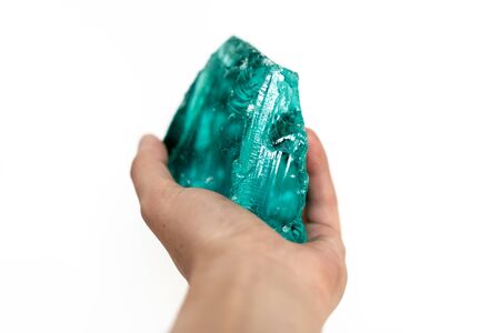 Large artificial semi-precious emerald stone in human hand isolated on the white background