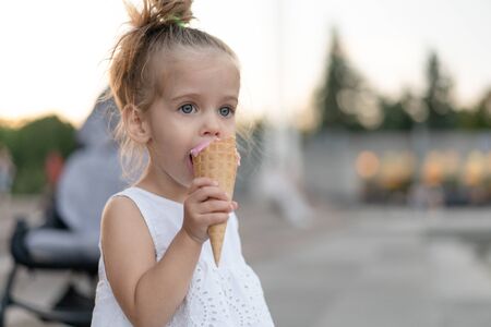 Little caucasian girl 3 years old eats ice cream closeup portrait. Summertime. Childhood  Child with...