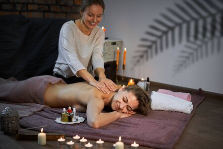 Relax and enjoy spa salon getting massage professional masseur Woman lying naked back relax on floor blanket Body care Hands treatment Acupressure trigger points Prevention back muscles painの写真素材