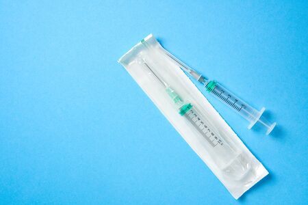 Two plastic disposable medical syringes open and package lie on blue background. Pharmaceutical Concept Health care and medicine. free Copy spaceの写真素材