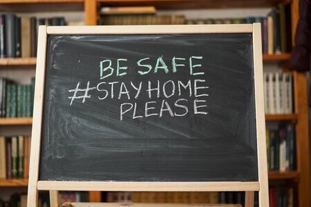 Hashtag stay at home. Outbreak Warning. written white chalk on blackboard in connection with epidemic of coronavirus worldwide. Covid 19 pandemic Text on black background with free space.の写真素材