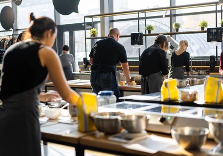 Culinary class. Back view of the process of cooking. Different unrecognizable people in gray apronsthe in the kitchen learn to cook. Cooking workshop. cook trainingの写真素材