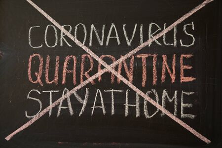 Inscription quarantine stay at home. Outbreak Warning. written white chalk on blackboard in connection with epidemic of coronavirus worldwide. Covid 19 pandemic Text on black backgroundの写真素材
