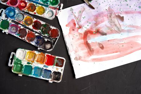 Set of watercolor paints on a black background. Brushes drawing. Creative background. School for teaching drawing. With copy space for textの写真素材