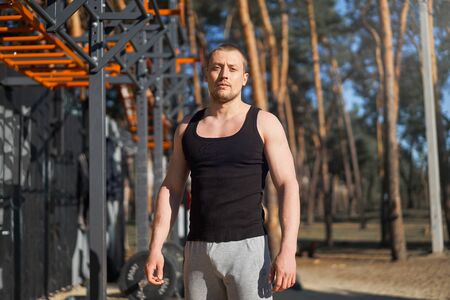 Athletic man standing outdoor gym workout. Handsome caucasian guy cross training nature public gym. Sportive people healthy lifestyle concept.の写真素材