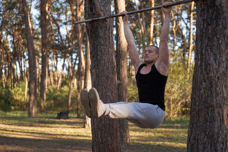 Handsome caucasian men pull-up outdoor workout cross training morning pumping arm abdominal...