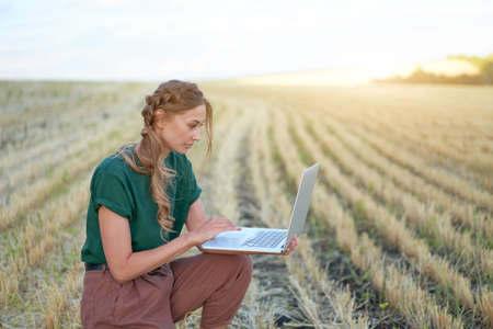 Woman farmer smart farming standing farmland smiling using laptop Female agronomist specialist research monitoring analysis data agribusiness Caucasian worker agricultural fieldの写真素材