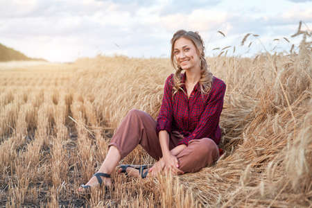 Woman farmer sitting farmland smiling Female agronomist specialist farming agribusiness Happy positive caucasian worker agricultural field dressed red checkered shirt and bandana Red plaid shirt.の写真素材