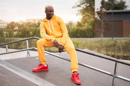 African-american smiling black man yellow hoodie outside Happy emotional afro model guy sitting skate park summer day Free space Positive emotionsの写真素材