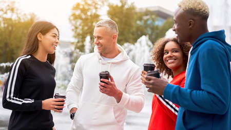 Multi-ethnic group teenage friends. African-american asian caucasian student spending time together Multiracial friendship Happy smiling People dressed colorful sportswear drink coffee outdoorの写真素材