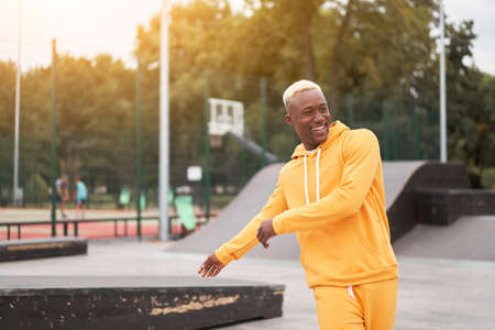 African-american smiling black man yellow hoodie outside Happy emotional afro model guy walking skate park summer day Free space Positive emotionsの写真素材