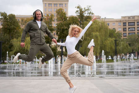 Couple in love walking outdoors park fountain Caucasian man woman walk outside after jogging dressed...