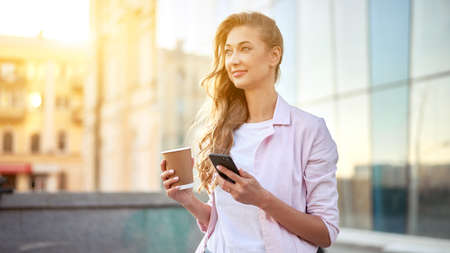 Businesswoman standing summer day near corporate building using smartphone teeth smiling Business...