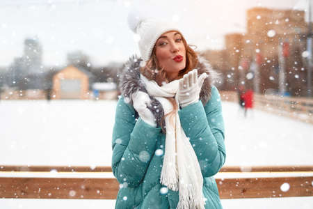 Beautiful lovely middle-aged girl curly hair warm winter jackets white knitted hat glove stands ice...