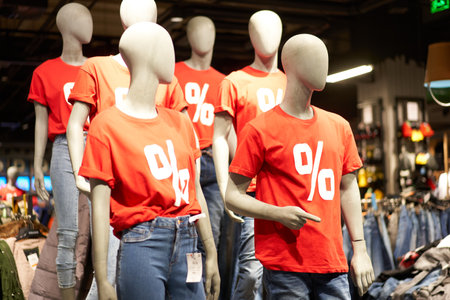 Percentage sign painted on a red t-shirt dressed on a mannequin stands in defocused store denoting big seasonal discountsの写真素材