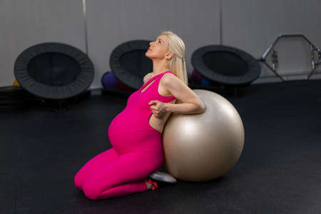 Pregnant woman exercise with fitness bal in gym Caucasian female workout fit ball Pregnancy Sport Healthy lifestyle conceptの写真素材