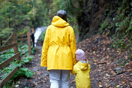 Rainy day Mother and little daughter walking after rain dressed yellow raincoat Happy family with one child. Positive emotionsの写真素材