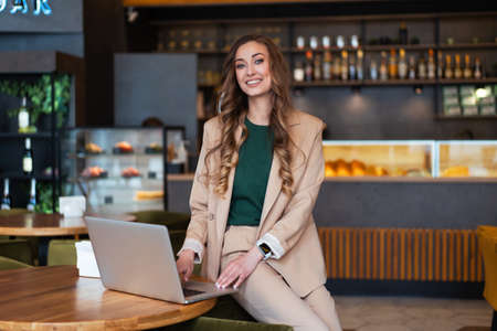 Business Woman Restaurant Owner Use Laptop In Hands Dressed Elegant Pantsuit Sitting On Table In Restaurant With Bar Counter Background Caucasian Female Business Person Indoorの写真素材