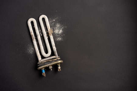 Damaged heating element of washing machine with scum and sediment on black backgroundの写真素材
