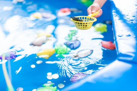 Child Fisher Catching Plastic Toy Fish On Pool Amusement Park Summer Day Little Girl Have Fun On Fishing Carnival Festival Entertainment For Childrenの写真素材