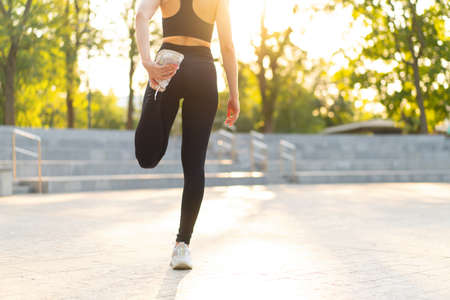 Woman runner stretching legs before exercising summer park morning Middle age athletic female...