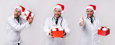 Handsome doctor white uniforme Santa Claus hat standing studio white background with red present box smile Medium shoot Holding Christmas gift box New Year Holiday Medicine conceptの写真素材