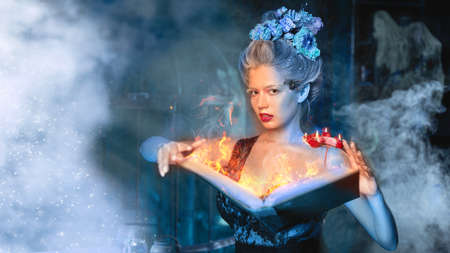Christmas fairy tale concept. Snow queen calling winter use book of spell with fire incantation....