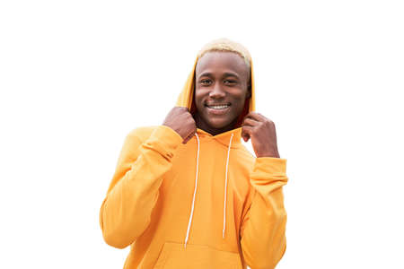 Young black man feeling happy, positive and successful, holding hood, achievements isolated on white background. African ethnicity male person yellow hair yellow hoodie in studioの写真素材