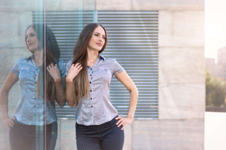 Business woman 35 years dressed stripe shirt with long hair standing near office building outdoor...