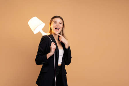 Creativity and innovative are keys to success. Concept of new idea and innovation with light lamp. Beautiful smiling caucasian woman holding lamp in hand and smile isolated. Creative idea concept.の写真素材