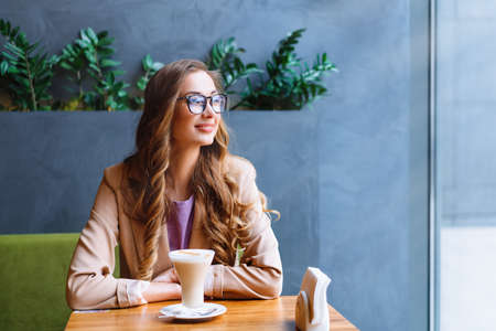 Business Woman Sitting Cafe Near Window Waiting Business Partner Caucasian Female Resting Cafeteria Drink Late Coffee Smile Looking outsideの写真素材