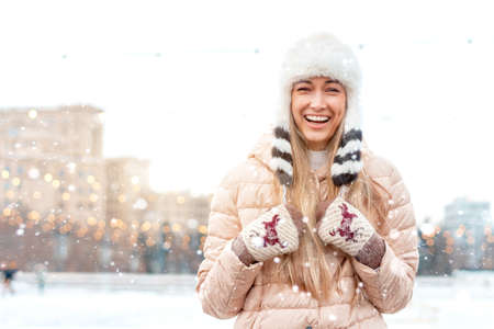 Happy winter time in big city charming girl standing street dressed funny fluffy hat. Enjoying snowfall, expressing positivity, smiling to camera, joyful cheerful mood, true emotions, Christmas moodの写真素材