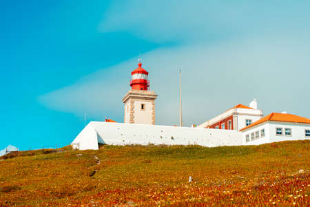 View of the Cabo da Roca Lighthouse. Sintra, Portugal. Portuguese Farol de Cabo da Roca is a cape which forms the westernmost point Eurasian land mass. Sunny summer day. Cloudy skyの写真素材