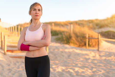 Athletic woman portrait outdoor. Caucasian female sportive woman standing on nature ocean beach. Confident middle age fit woman summer dayの写真素材