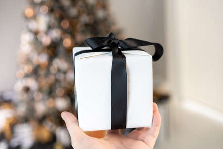 Christmas present gift box stacked close up. Holiday sale concept. Many gift box black, white, orange color with gold ribbon and light garlandの写真素材