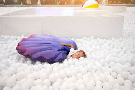 Happy little girl playing white plastic balls pool in amusement park. playground for kids. Active leisure for children.の写真素材