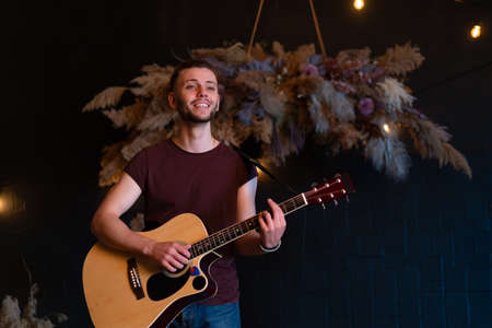 Guitarist plays classical guitar on stage in concert Handsome young hipster male guitar player...