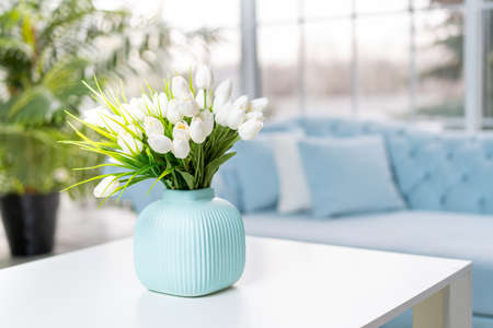luxury house interior. Elegant living room Modern Interior design. White Living Room Tulip flowers standing vase on coffee table With big panoramic window on backgroundの写真素材