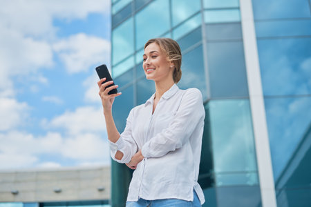 Businesswoman successful woman business person standing outdoor corporate building exterior cell phone Pensive elegance cute caucasian professional business woman middle age dreaming with mobile phoneの写真素材