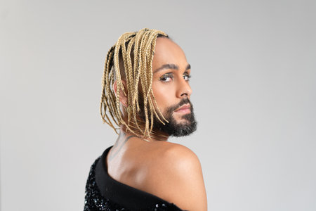 Man wearing stylish jacket with sequins on naked body. Afro-american homosexual male posing in photo studio on white background. bearded gay with beard and make up close up portraitの写真素材