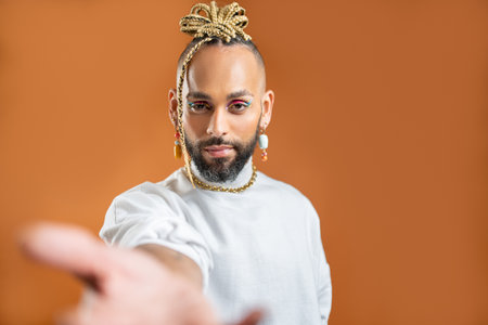 African-american gay with bright make up reaching empty open palm hand towards camera. Mock up...