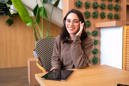 Modern technologies and communication. Portrait of happy woman with tablet computer sitting at her desk. Young female person studying or working online on touch padの写真素材