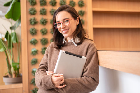 Woman student with tablet computer standing smile and looking camera. Female person studying or working online on touch pad. Modern technologies and communication.の写真素材
