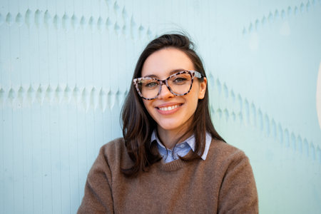 Happy woman in glasses outdoor on blue color background. positive people concept. Smiling girl in eyeglasses looking at camera. copy spaceの写真素材