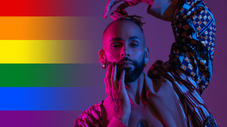 Neon light studio close-up portrait handsome black gay man looking camera. Seductive sexy man, transgender person dance in ultraviolet light on rainbow LGBT flag. nightclub dancer night life conceptの写真素材