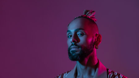 Neon light studio close-up portrait handsome black gay man looking camera. Seductive sexy man wear make up, transgender person in ultraviolet light. LGBT nightclub and nightlife conceptの写真素材
