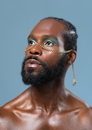 Confident african-american bearded gay man with bright makeup isolated on blue background, Close up portrait. Exudes sense of pride and individuality. Diversity power of personal style.の写真素材