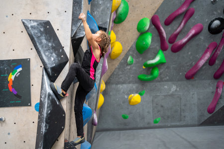 Full length of sporty little girl in active wear climbing artificial wall. Female child practicing bouldering in sports center. Healthy lifestyle concept.の写真素材