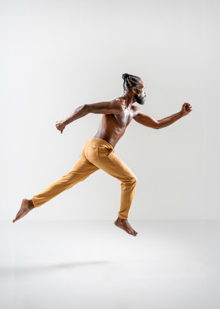 Full length of shirtless African American gay man running isolated on white background. Side view of athletic man jogging in white studio. Equality concept.の写真素材