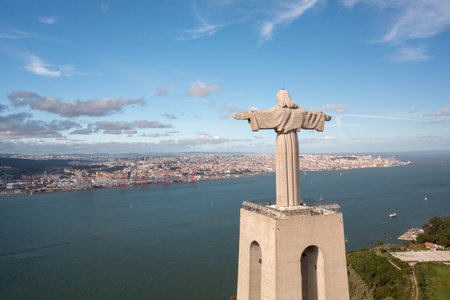 Aerial view monument Sanctuary of Christ the King. Majestic scenery statue with cityscape Almada and Tagus Riverin background. Birds eye view Catholic monument and cityの写真素材